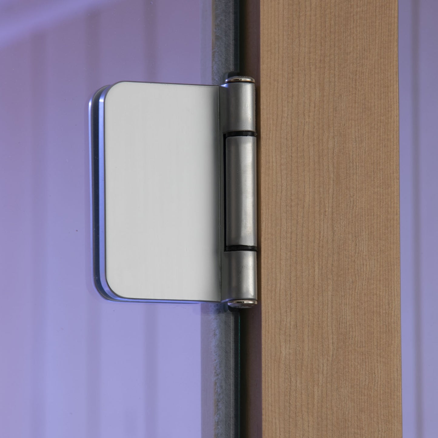 Close-up of a metallic door hinge on a wooden door with a purple background