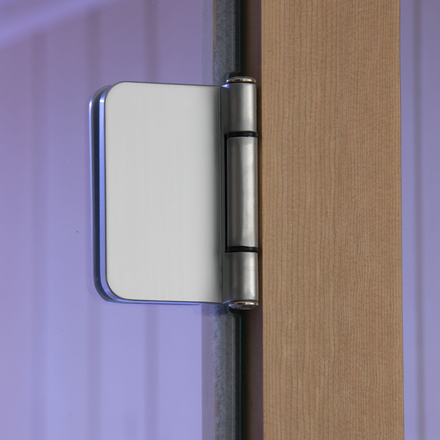 Close-up of a metallic door hinge on a wooden door with a purple background