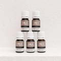 Five Kiva Wellness Clarity eucalyptus essential oil bottles with white caps displayed on a pale pedestal.