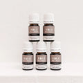 Five Kiva Wellness Purity peppermint essential oil bottles with white caps displayed on a pale pedestal.