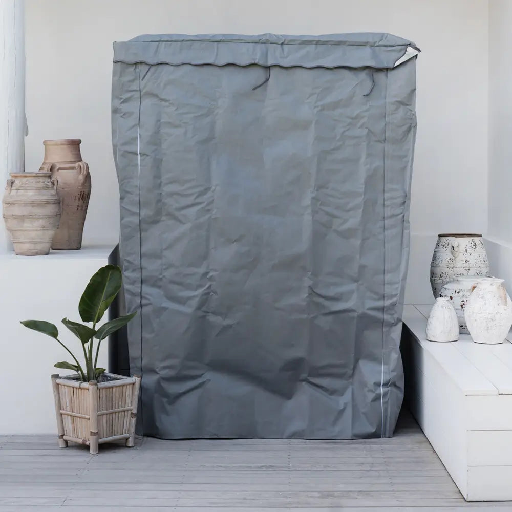 Grey Kiva Wellness sauna cover fitted over a cabin on a deck beside potted plants and decorative baskets.