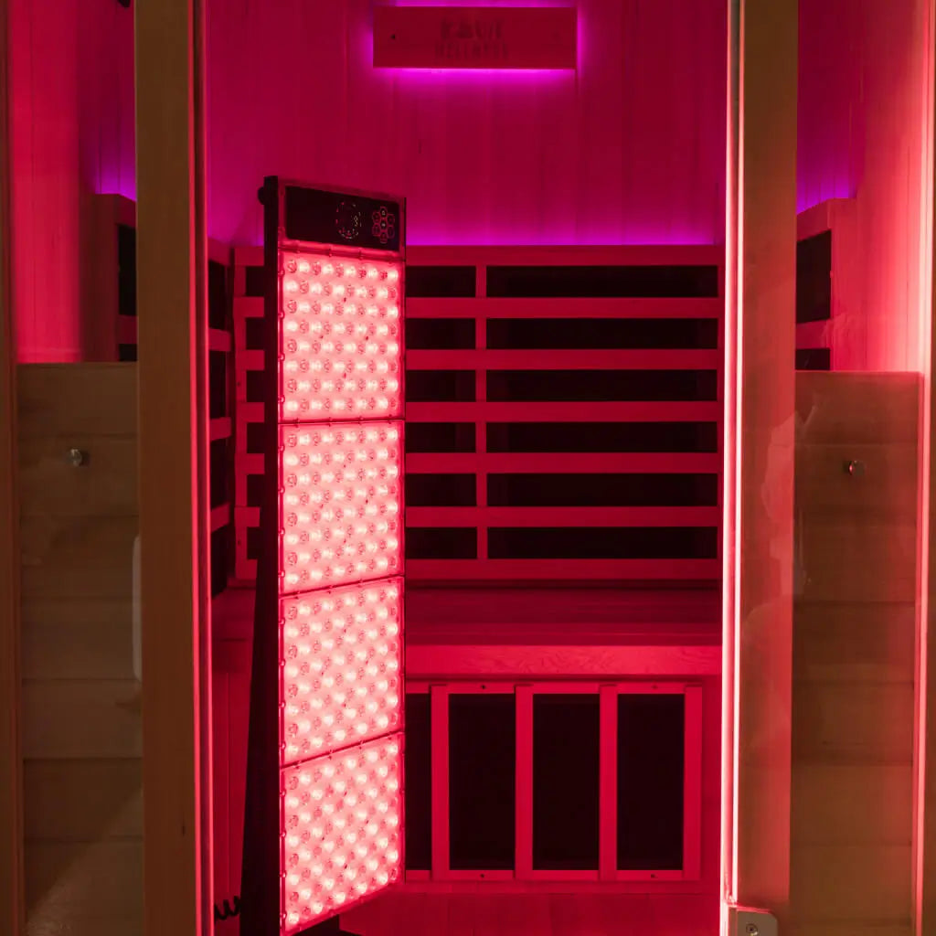 Kiva Wellness Radiance red light therapy panel illuminating the timber interior of an empty sauna.