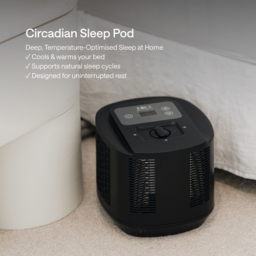 A circadian sleep pod placed on a carpeted floor next to a white cylindrical container, with white bedding in the background.