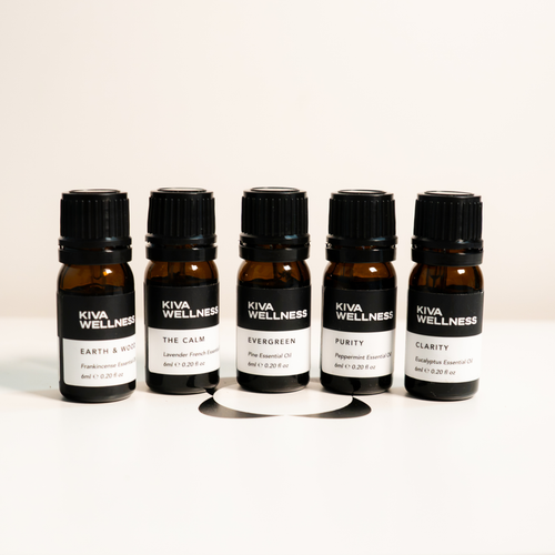 Five essential oils arranged in a row on a white surface against a light beige background.