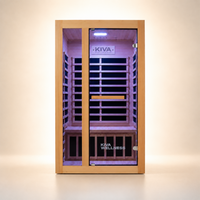 A Kiva Wellness infrared sauna with a light wood exterior, glass door, and a purple interior illuminated by built-in lights, shown against a clean beige studio background.