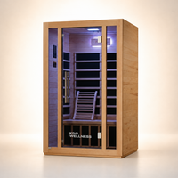A Kiva Wellness infrared sauna with a light natural wood exterior, glass door, and a dark interior with wooden benches and a backrest, shown on a clean beige studio background.