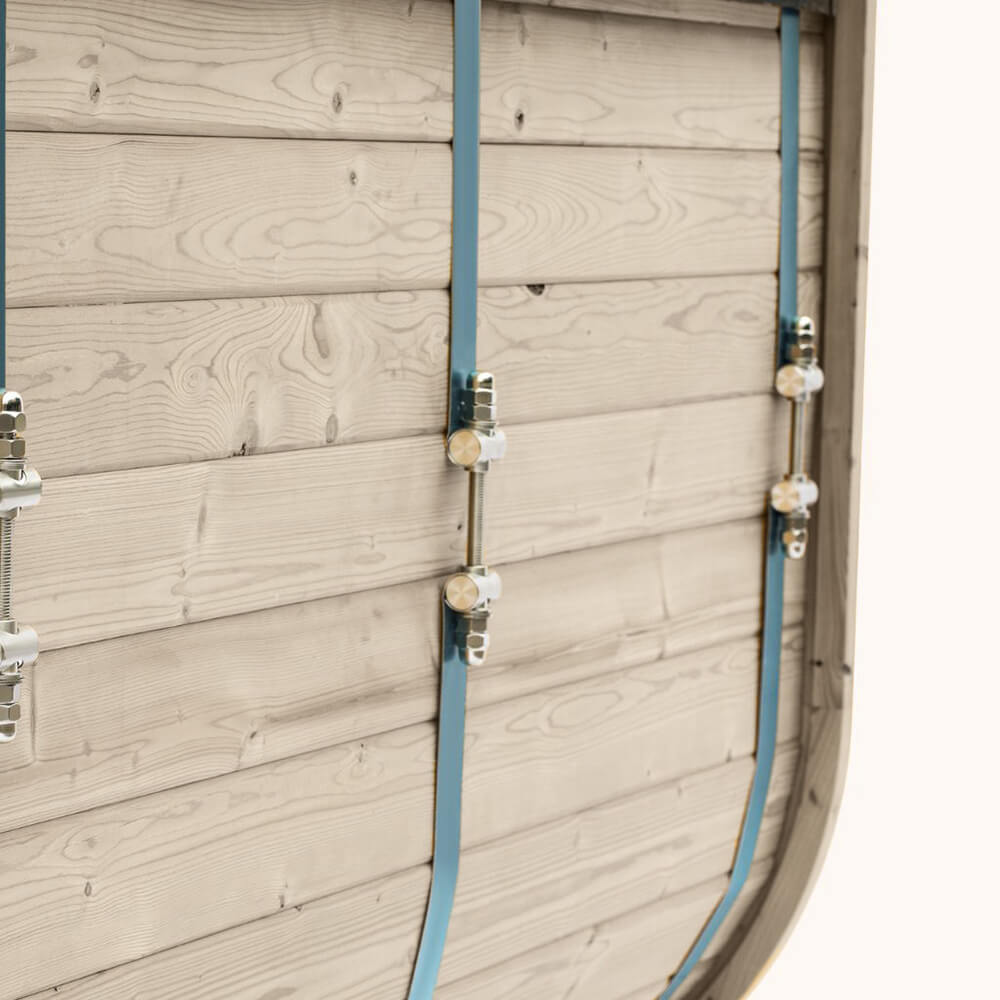 Close view of pale timber outdoor sauna cladding with metal retaining bands and adjustable fasteners.