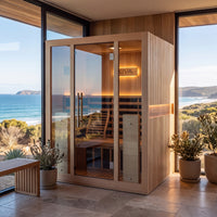 Radiance Pro 3 Person Full Spectrum Infrared WiFi Sauna, situated in a sunlit room with large windows overlooking a coastal ocean view