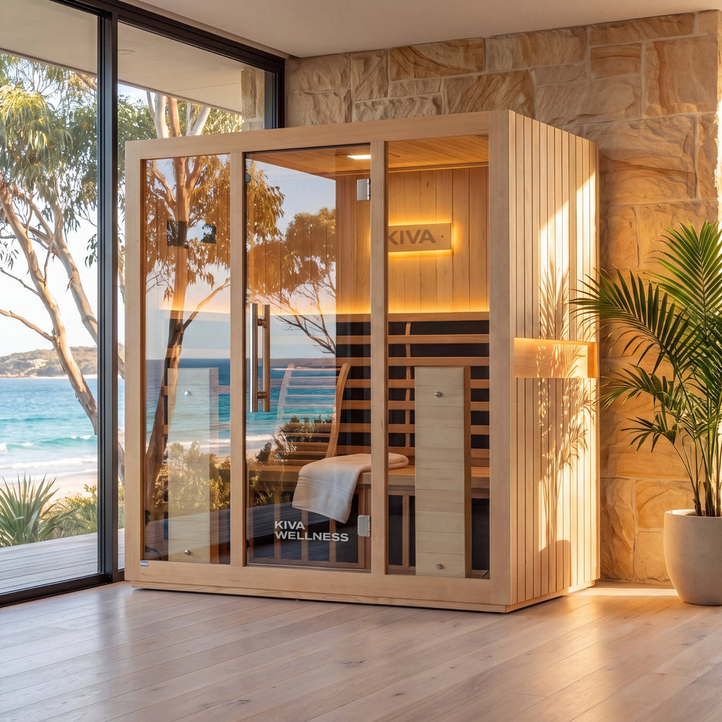 Kiva Wellness Radiance Pro 4 person sauna beside large windows, a stone wall and a potted palm with sea views.