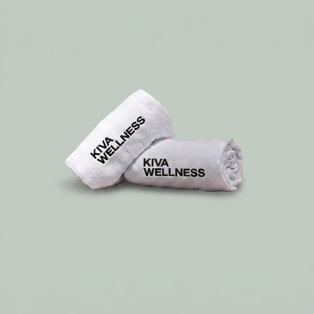 Two rolled white sauna towels displayed on a solid sage green background.