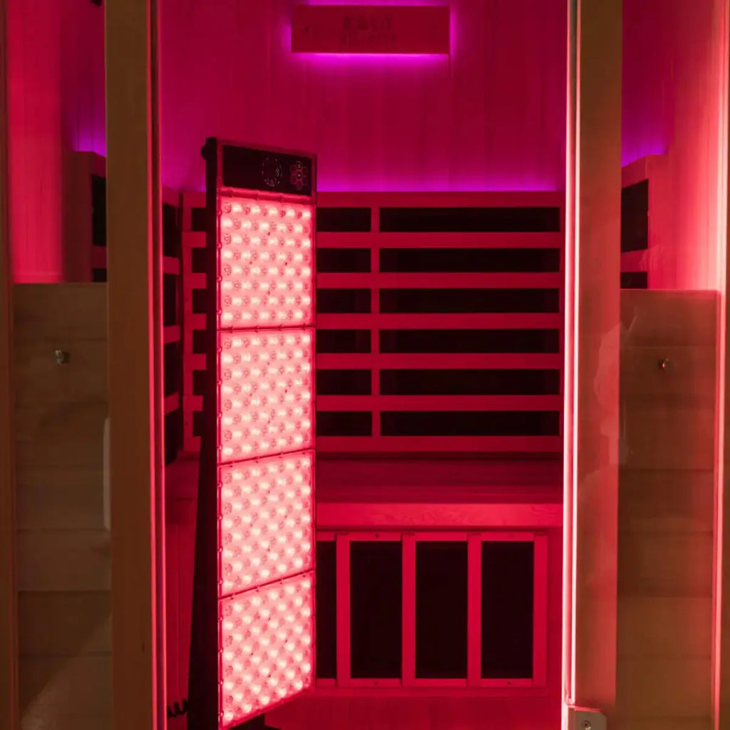 Kiva Wellness Radiance red light therapy panel illuminating the timber interior of an empty sauna.