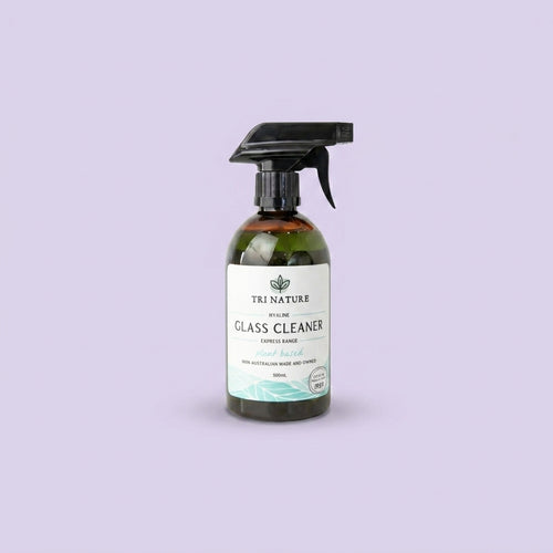 A 500ml spray bottle of Tri Nature Glass Cleaner set against a solid lavender background.